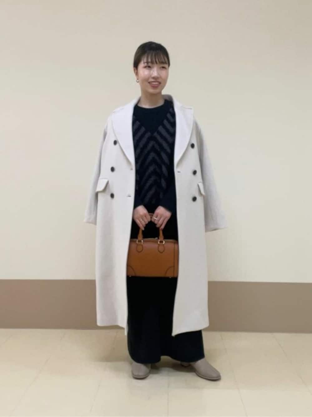 ブラック系のワンピース、ベージュ系のチェスターコート、ベージュ系のブーツを着用したレディースの秋コーディネートの1枚目の写真