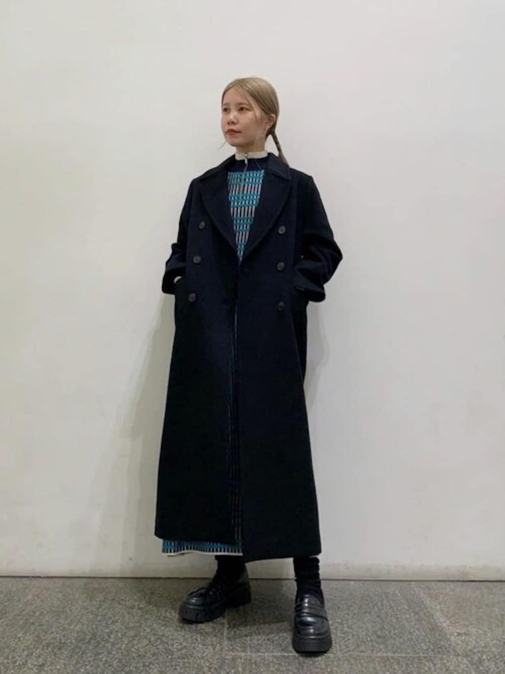 ブルー系のワンピース、ブラック系のチェスターコートを着用したレディースの秋コーディネートの1枚目の写真