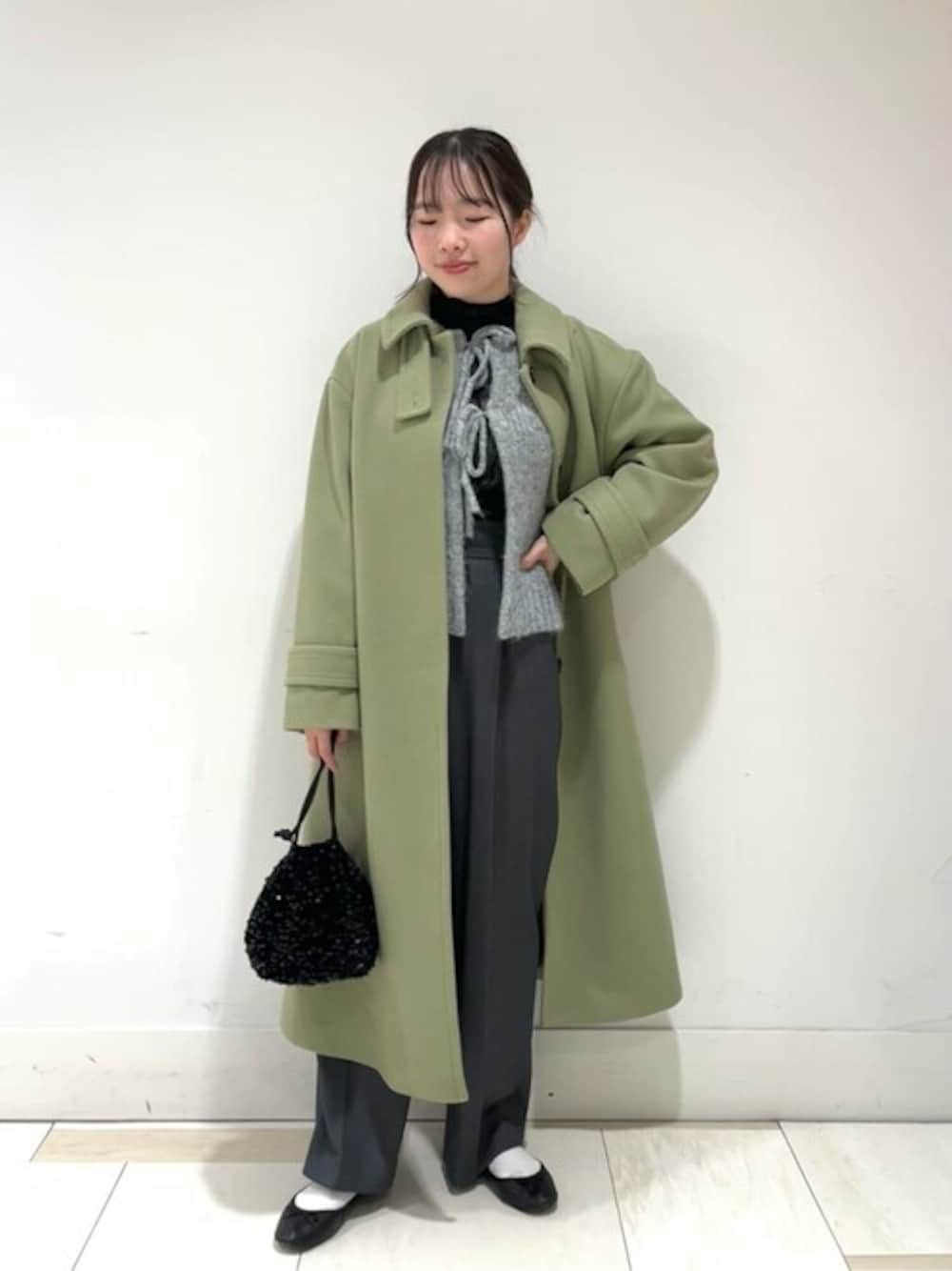 グレー系のスラックス、ブラック系のビジネスバッグ、ブラック系のTシャツ/カットソーを着用したレディースの冬コーディネートの1枚目の写真