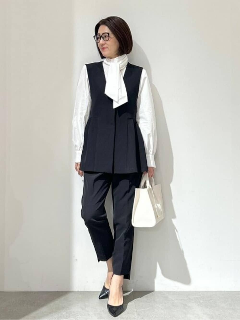 ブラック系のベスト、ホワイト系のシャツ/ブラウス、ブラック系のその他パンツを着用したレディースの冬コーディネートの1枚目の写真