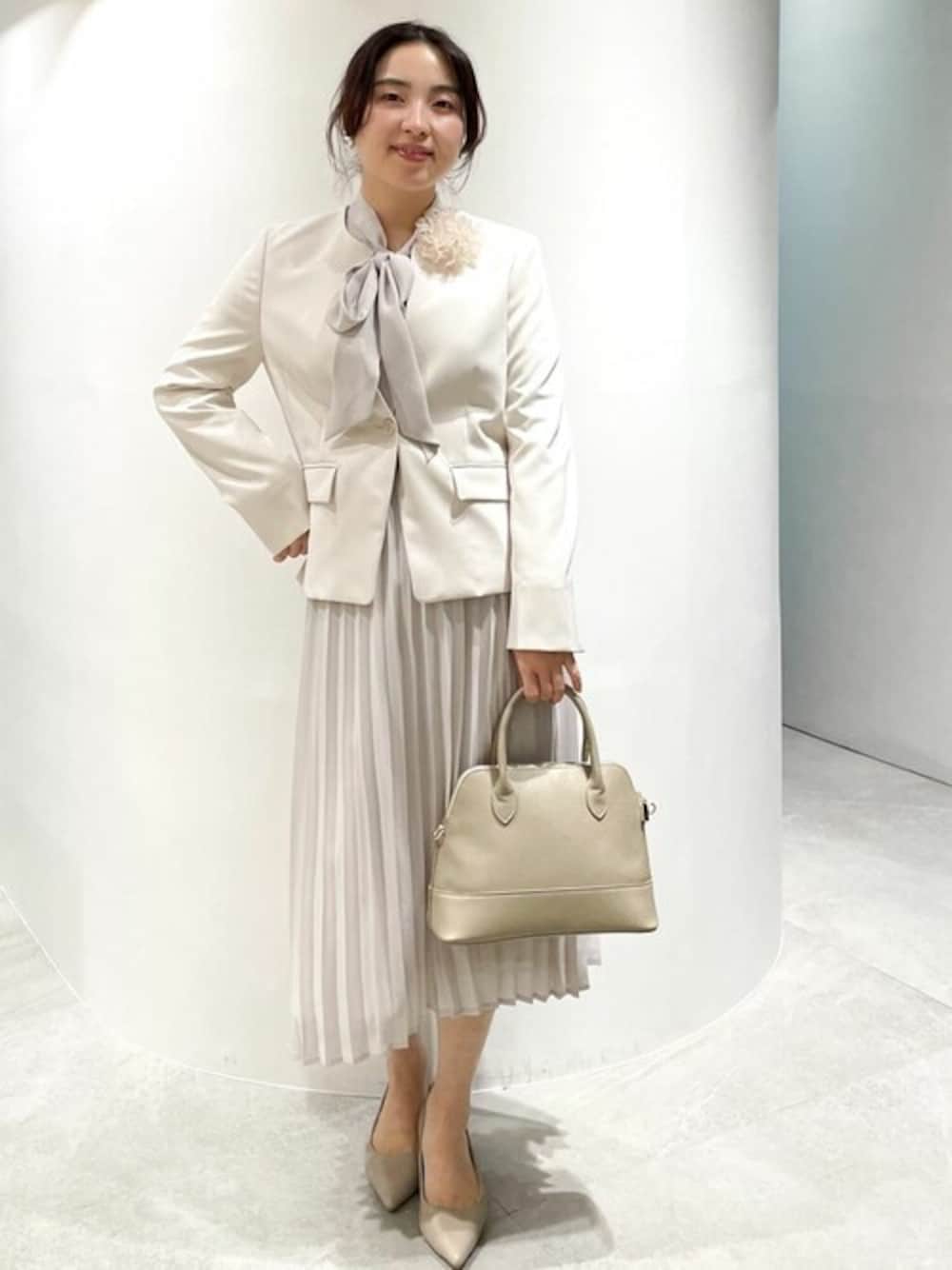 ベージュ系のノーカラージャケット、ベージュ系のワンピース、ベージュ系のハンドバッグを着用したレディースの冬コーディネートの1枚目の写真