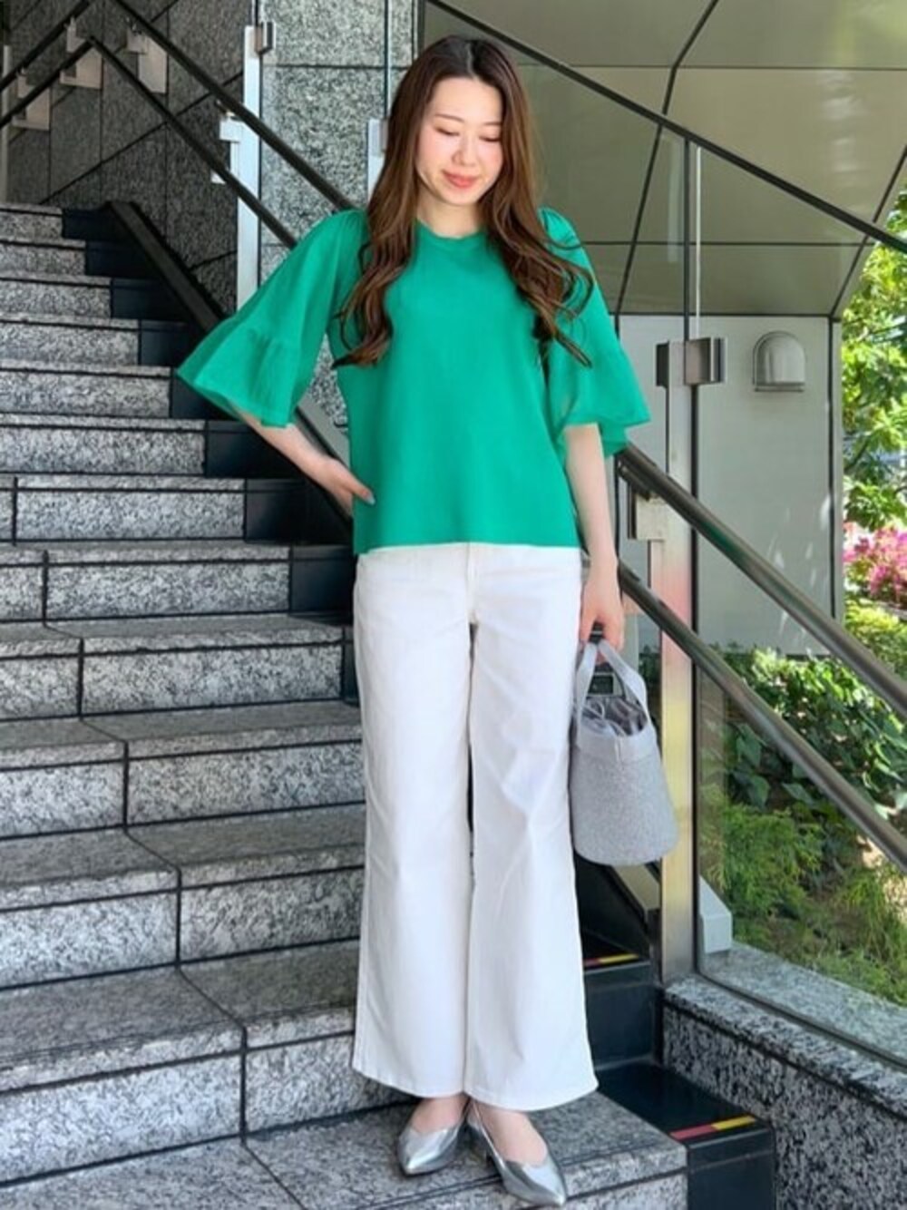 グリーン系のニット/セーター、ホワイト系のデニムパンツ、シルバー系のトートバッグを着用したレディースの春コーディネートの1枚目の写真