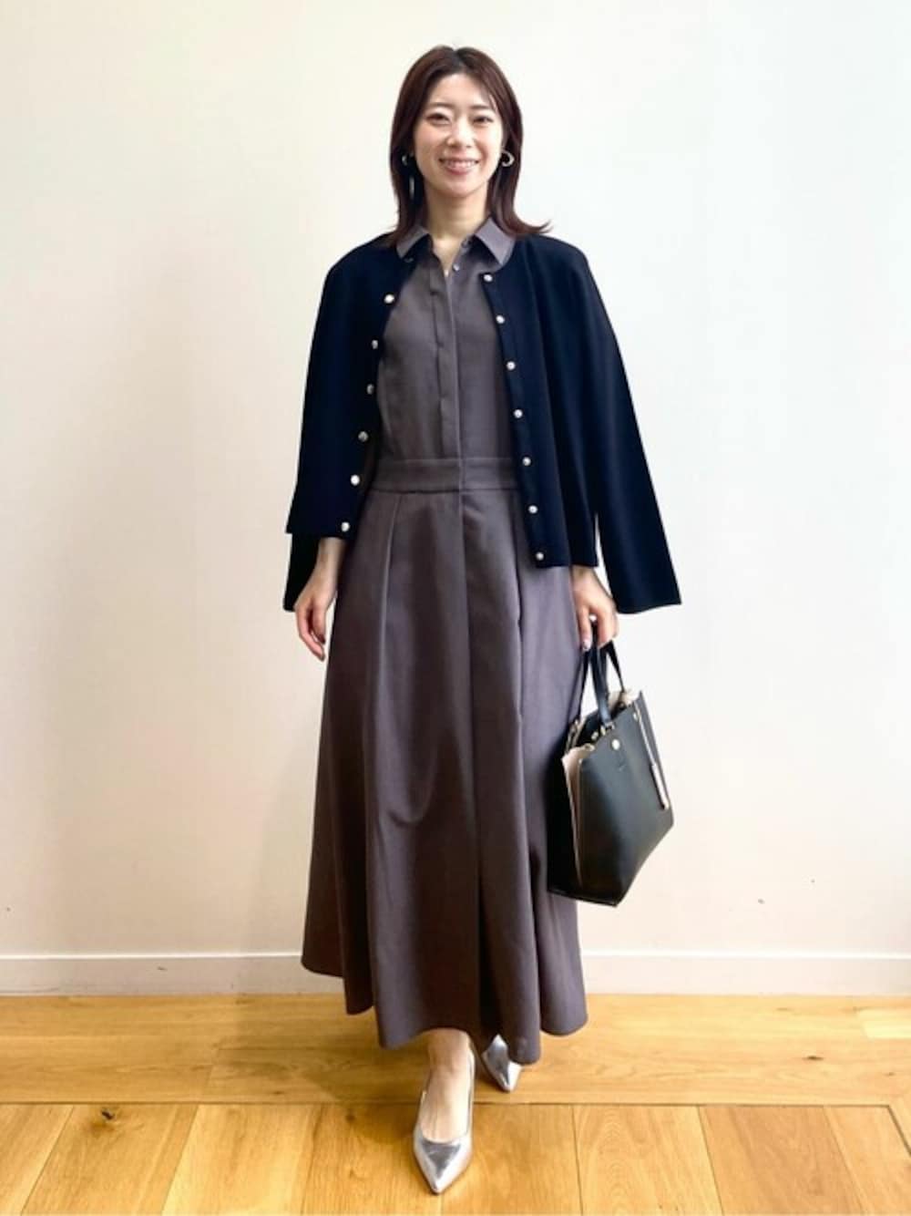 ブラック系のカーディガン/ボレロ、ブラウン系のワンピース、ブラック系のトートバッグを着用したレディースの春コーディネートの1枚目の写真