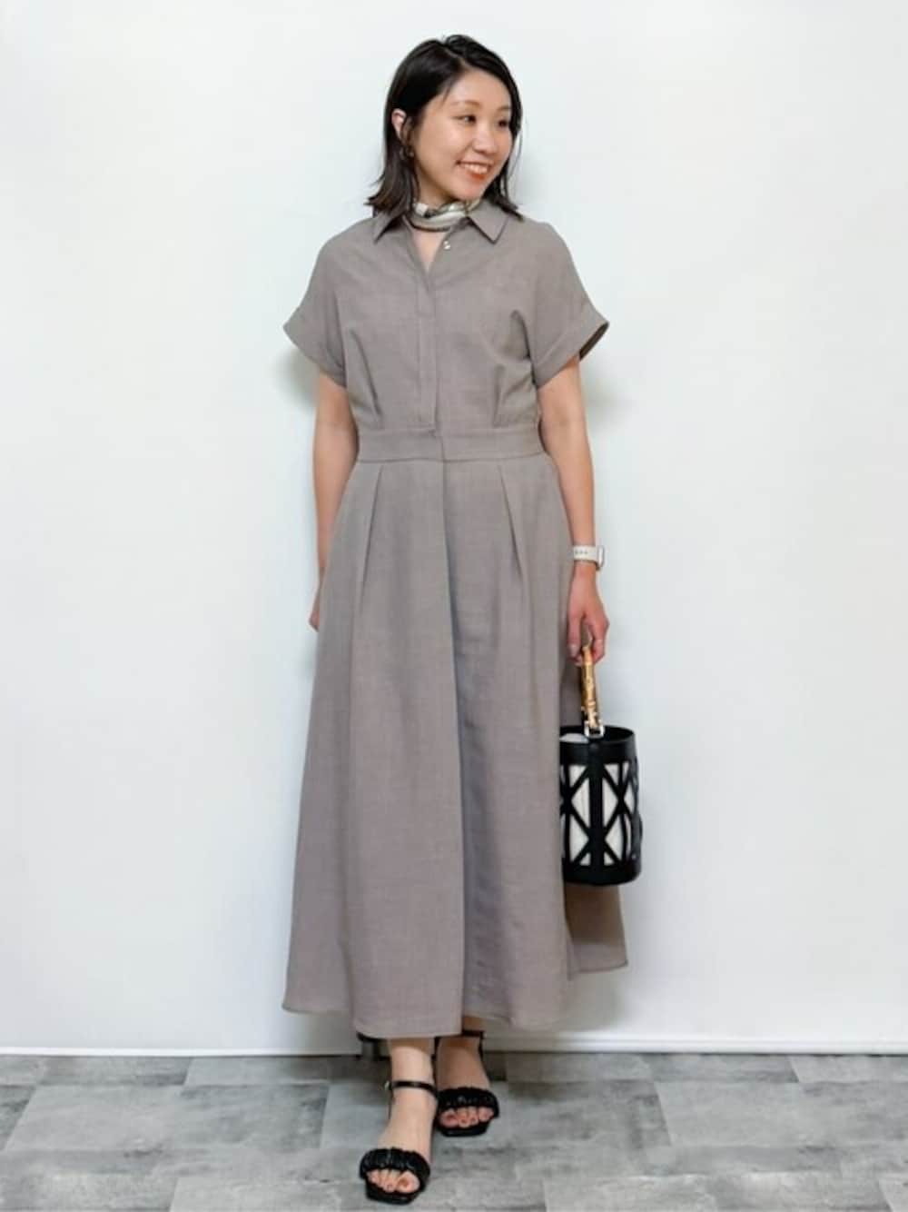 ベージュ系のワンピース、ブラック系のハンドバッグ、ブラック系のサンダルを着用したレディースの夏コーディネートの1枚目の写真