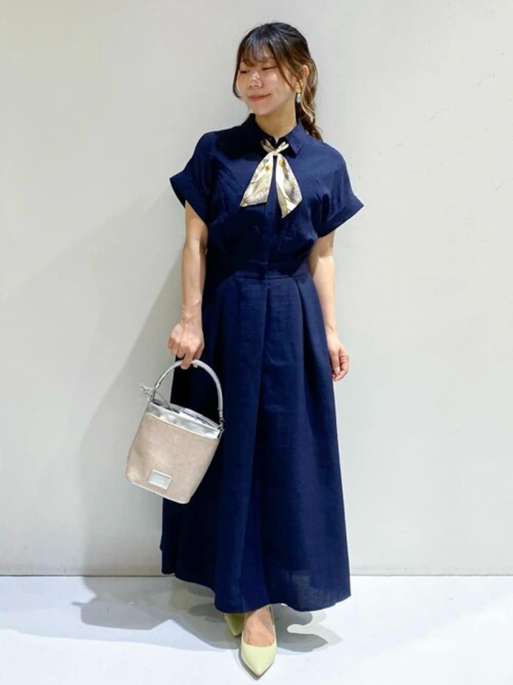 ブルー系のワンピース、シルバー系のショルダーバッグ、イエロー系のパンプスを着用したレディースの春コーディネートの1枚目の写真