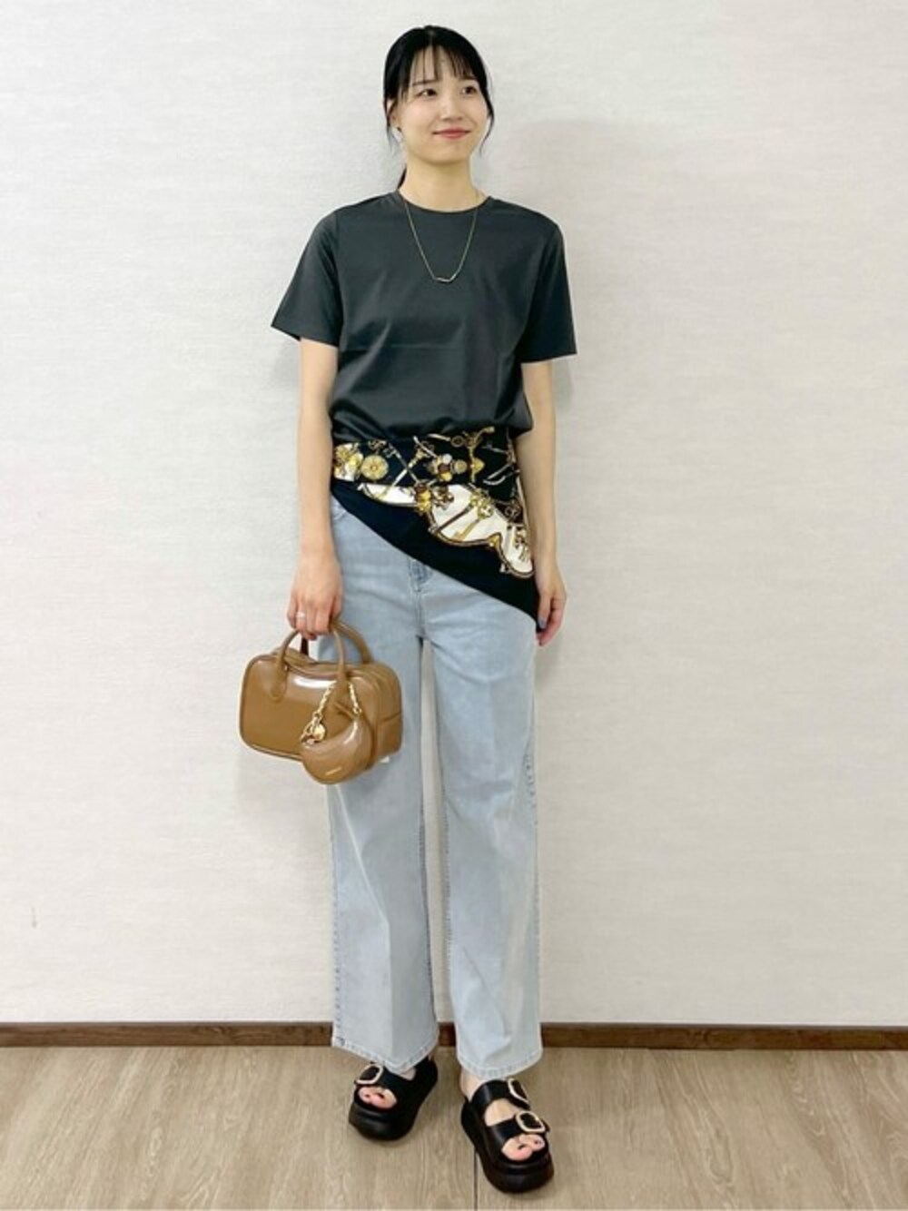 グレー系のTシャツ/カットソー、ブルー系のデニムパンツ、ベージュ系のショルダーバッグを着用したレディースの夏コーディネートの1枚目の写真
