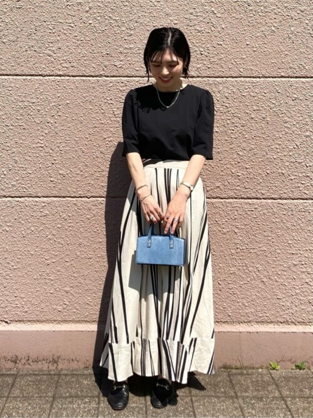 ブラック系のTシャツ/カットソー、ホワイト系のスカート、ブルー系のショルダーバッグを着用したレディースの夏コーディネートの1枚目の写真