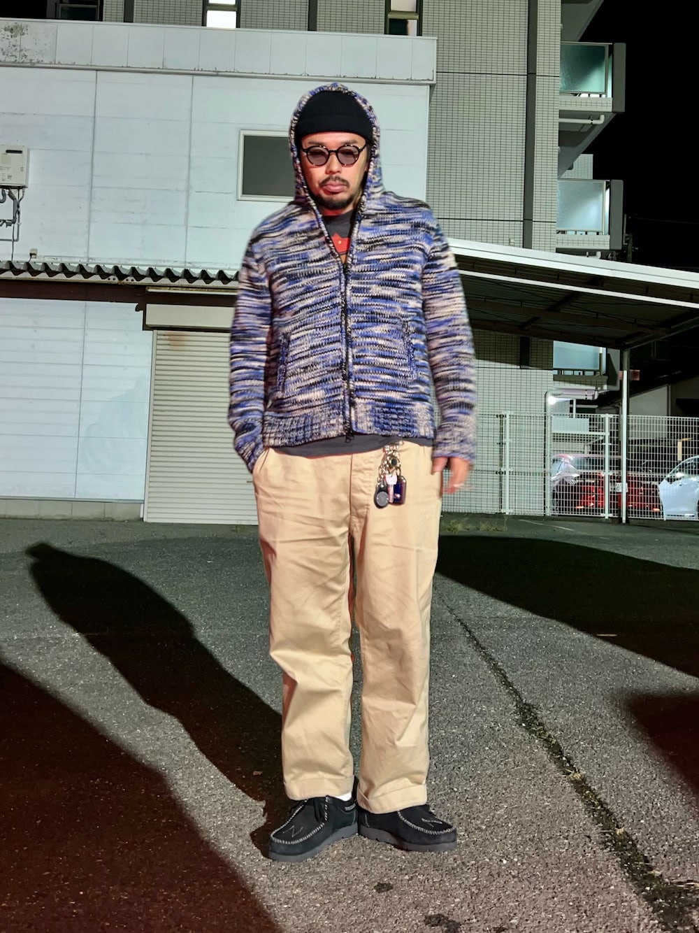 ブルー系のニット/セーター、ブラック系のTシャツ/カットソー、ベージュ系のチノパンツを着用したメンズの秋コーディネートの1枚目の写真