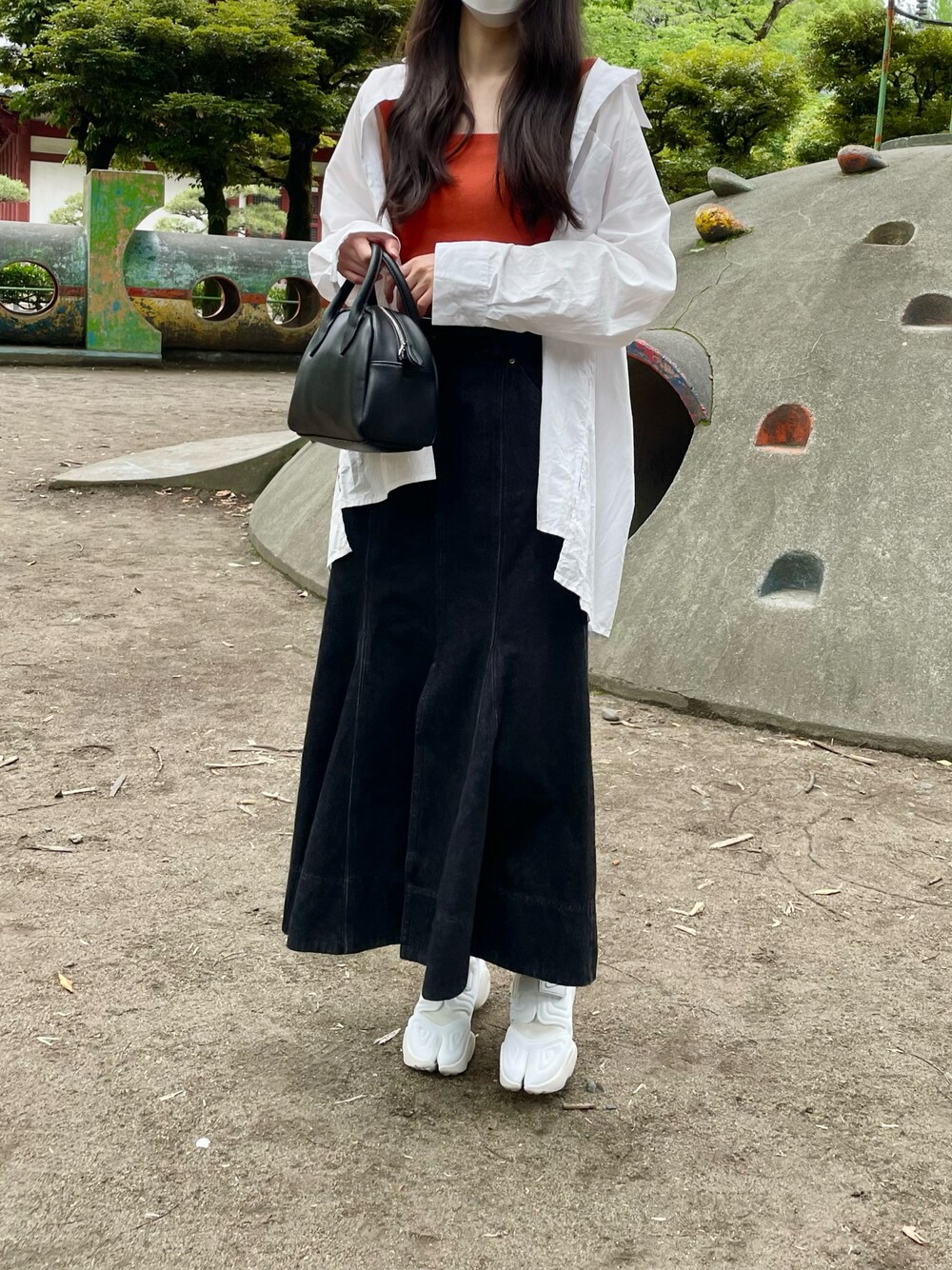 ブラック系のボストンバッグ、ブラック系のスカート、ホワイト系のスニーカーを着用したレディースの夏コーディネートの1枚目の写真
