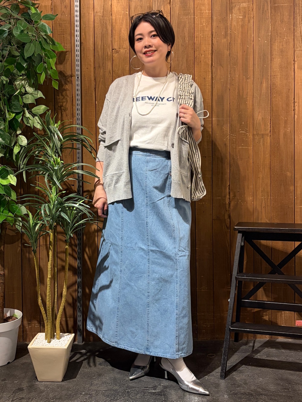 グレー系のニット/セーター、ブルー系のスカート、ホワイト系のTシャツ/カットソーを着用したレディースの秋コーディネートの1枚目の写真