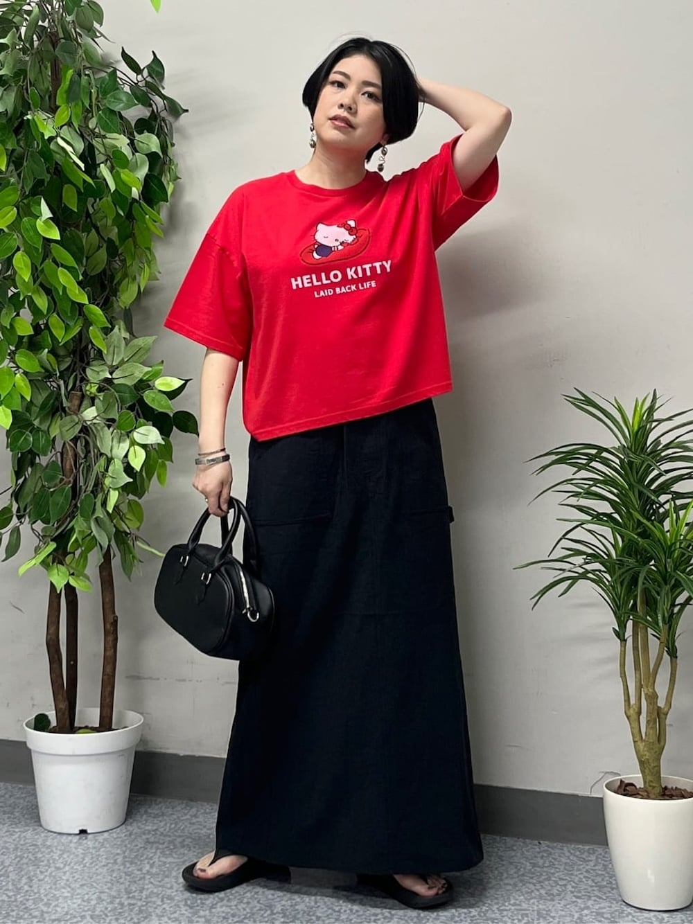 レッド系のTシャツ/カットソー、ブラック系のスカート、ブラック系のショルダーバッグを着用したレディースの春コーディネートの1枚目の写真