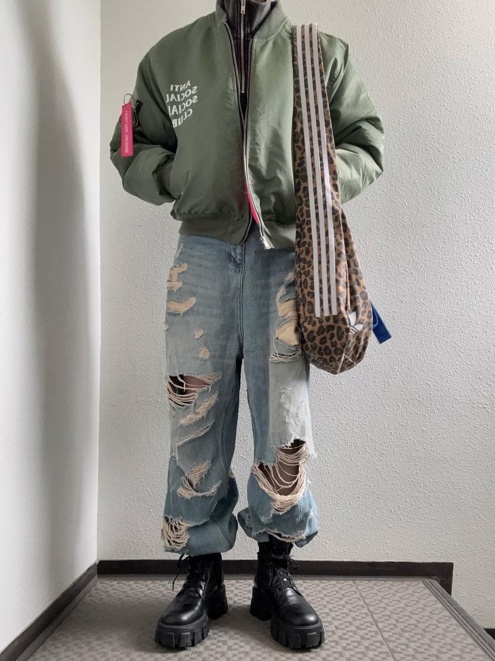 ブルー系のデニムパンツ、ブラウン系のショルダーバッグ、グレー系のトップスを着用したレディースの冬コーディネートの1枚目の写真