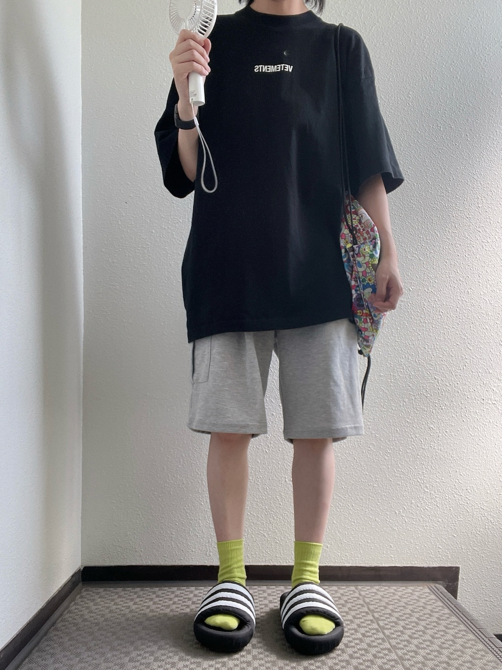 ブラック系のTシャツ/カットソー、グレー系のパンツ、ブラック系のサンダルを着用したレディースの秋コーディネートの1枚目の写真