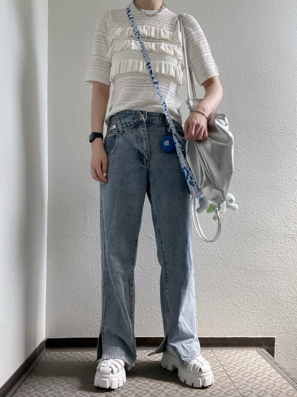 ホワイト系のニット/セーター、シルバー系のバックパック/リュック、ブルー系のデニムパンツを着用したレディースの夏コーディネートの1枚目の写真