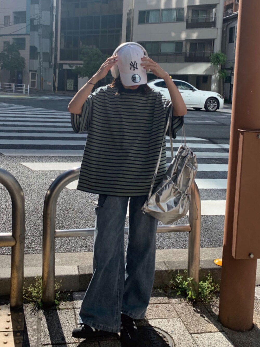 グリーン系のTシャツ/カットソー、シルバー系のバックパック/リュック、ブルー系のデニムパンツを着用したレディースの春コーディネートの1枚目の写真