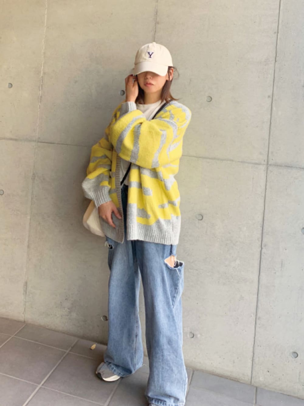 イエロー系のカーディガン/ボレロ、ブルー系のデニムパンツ、グレー系のスニーカーを着用したレディースの秋コーディネートの1枚目の写真