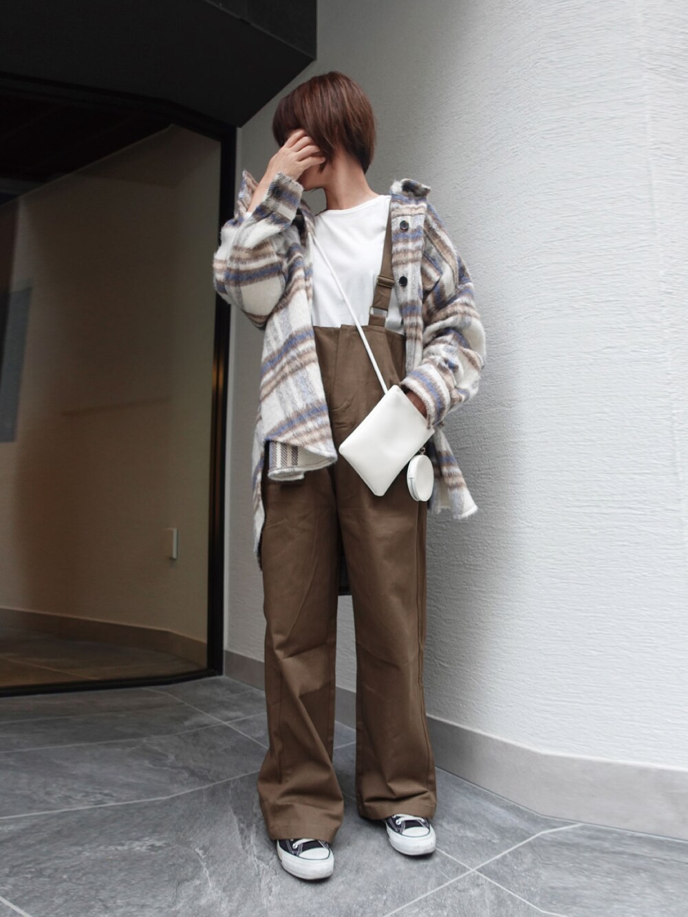 ブラウン系のサロペット/オーバーオール、ホワイト系のTシャツ/カットソー、ホワイト系のシャツ/ブラウスを着用したレディースの秋コーディネートの1枚目の写真