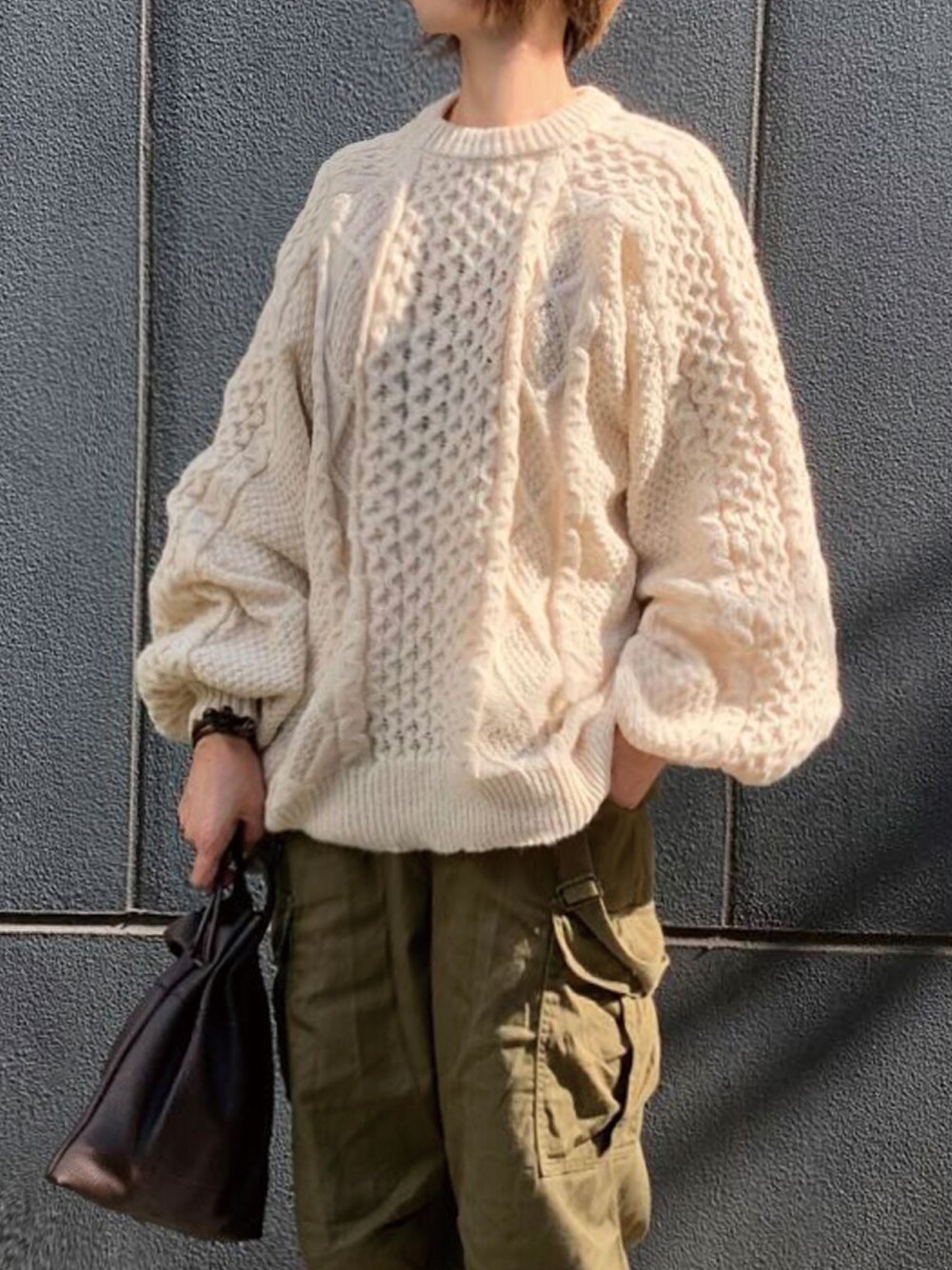 ホワイト系のニット/セーター、ホワイト系のTシャツ/カットソー、グリーン系のカーゴパンツを着用したレディースの秋コーディネートの1枚目の写真