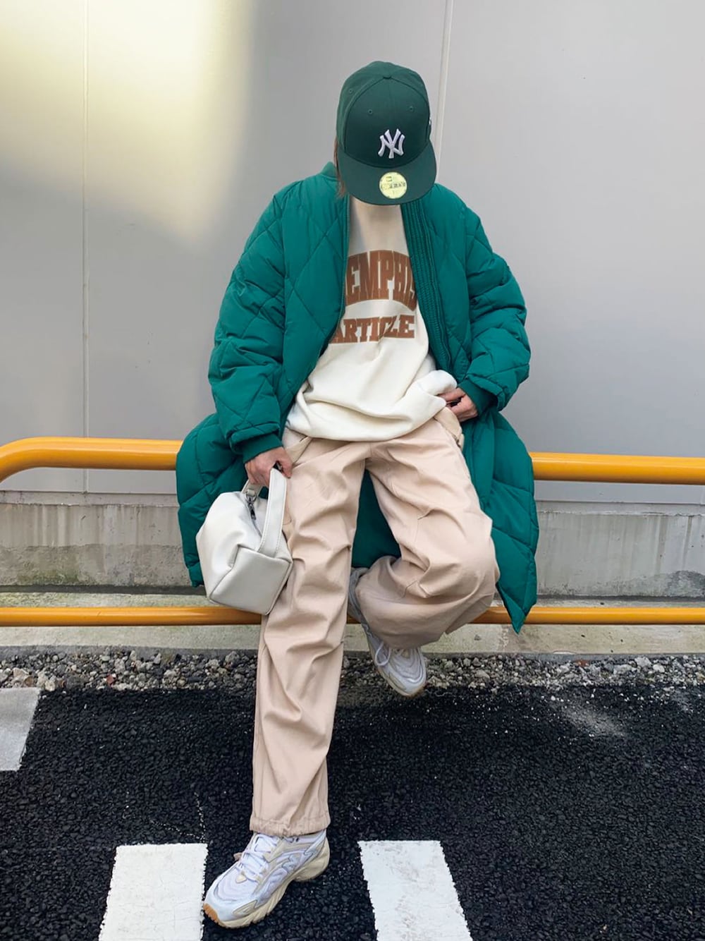 グリーン系のダウンジャケット/コート、ベージュ系のスウェット、ホワイト系のショルダーバッグを着用したレディースの秋コーディネートの1枚目の写真