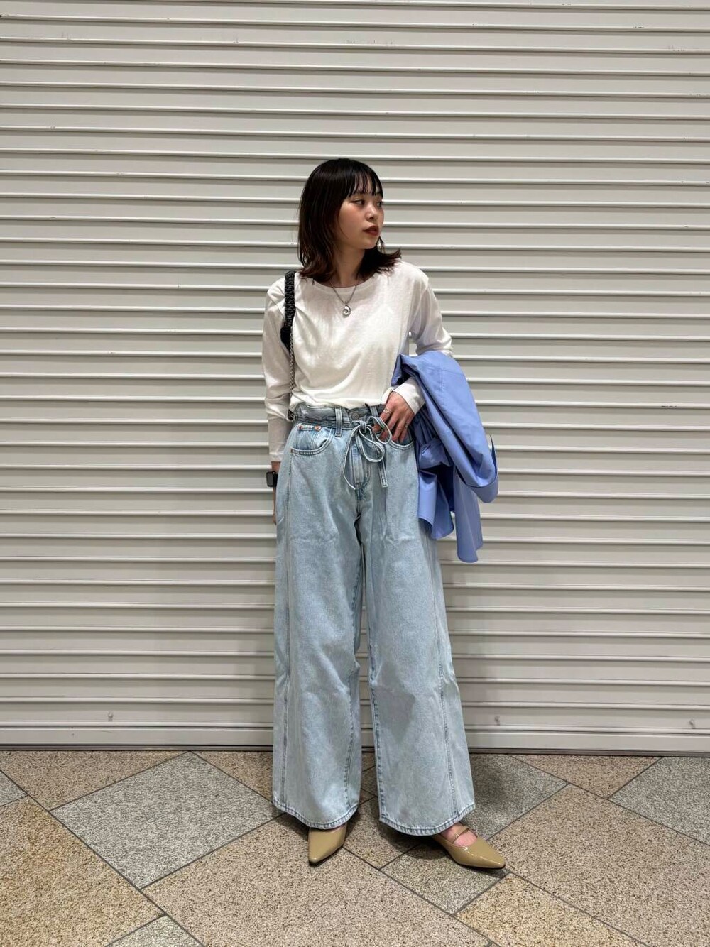 ホワイト系のTシャツ/カットソー、ベージュ系のパンプス、ブルー系のデニムパンツを着用したレディースの冬コーディネートの1枚目の写真