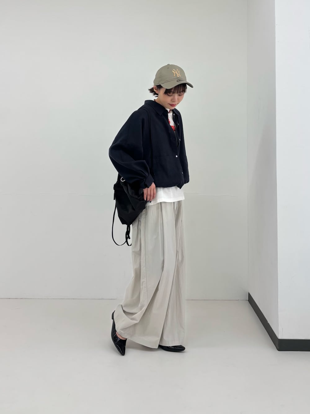 ブラック系のバックパック/リュック、ブラック系のパンプス、ブルー系のシャツ/ブラウスを着用したレディースの春コーディネートの1枚目の写真