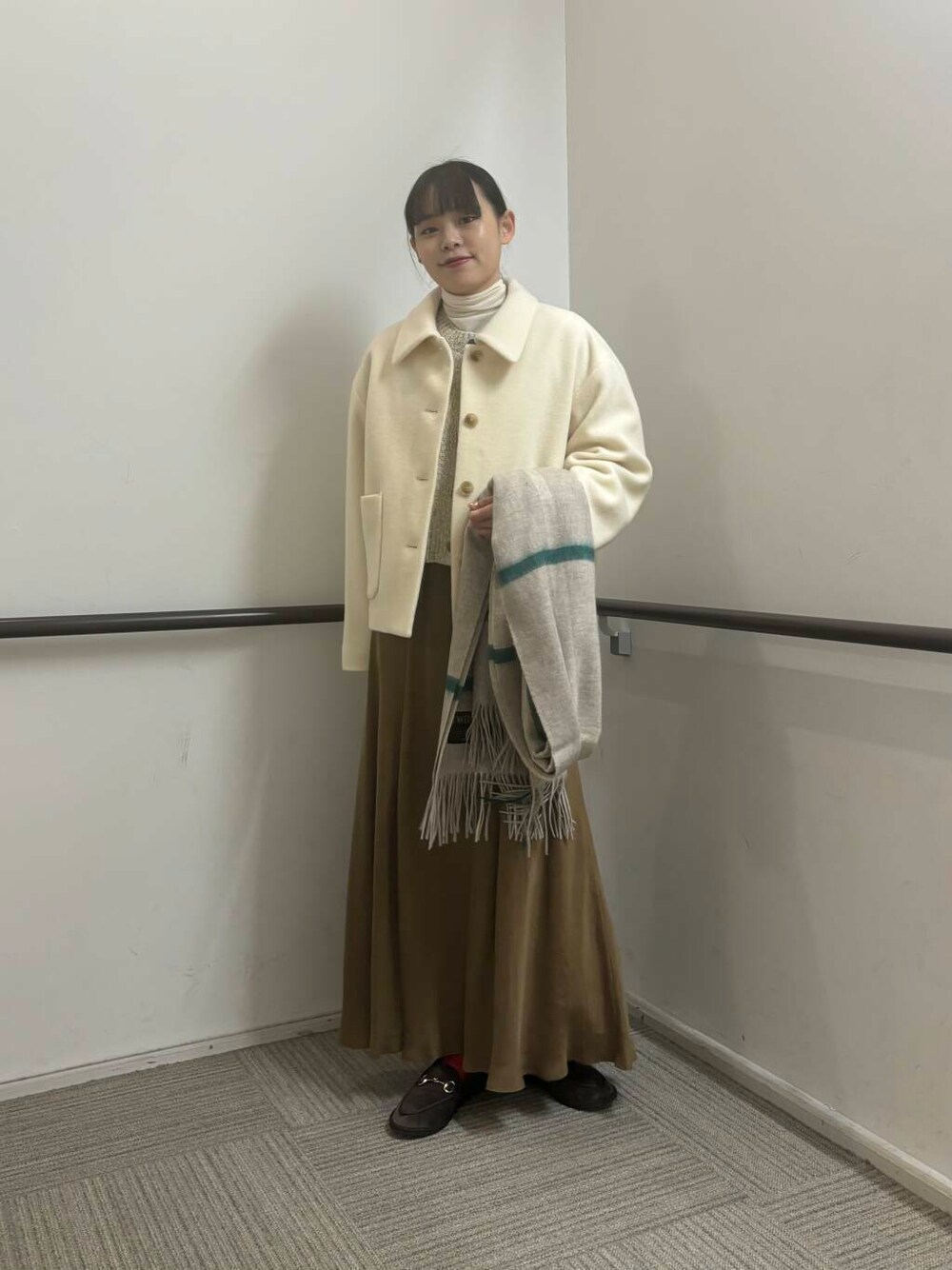 ホワイト系のその他アウター、イエロー系のスカート、ホワイト系のカーディガン/ボレロを着用したレディースの冬コーディネートの1枚目の写真