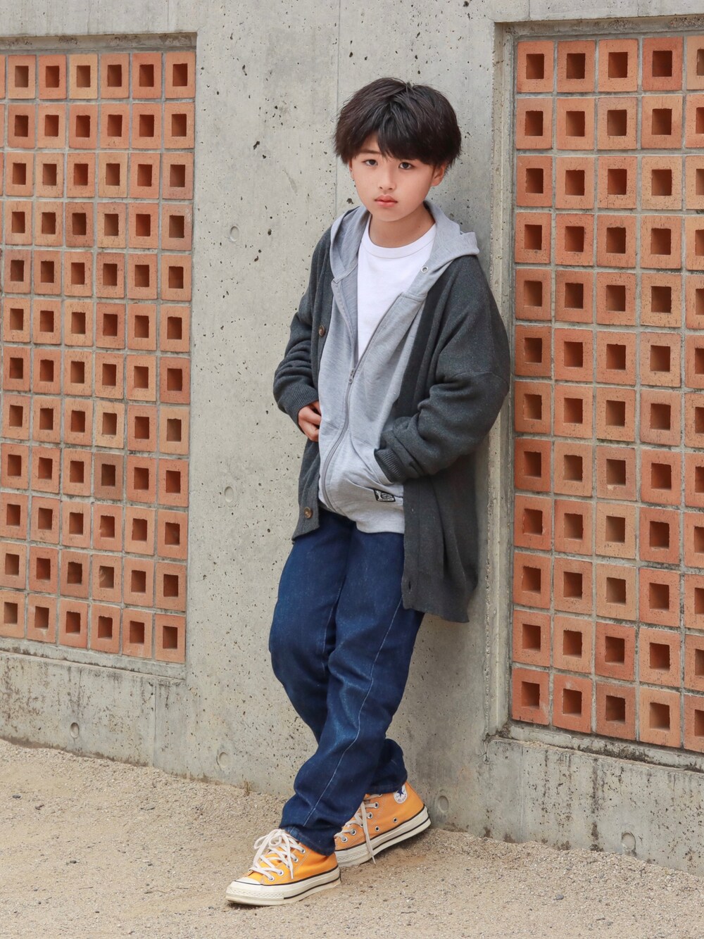 グレー系のカーディガン/ボレロ、ブルー系のデニムパンツ、イエロー系のスニーカーを着用したキッズの秋コーディネートの1枚目の写真