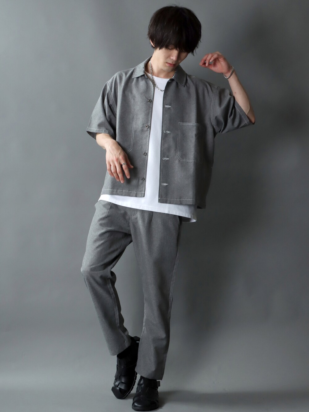 グレー系のセットアップ、ホワイト系のTシャツ/カットソー、シルバー系のネックレスを着用したメンズの夏コーディネートの1枚目の写真