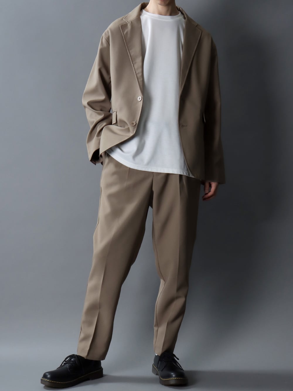 ベージュ系のセットアップ、ブラック系のドレスシューズ、ブラック系のベルトを着用したメンズの春コーディネートの1枚目の写真