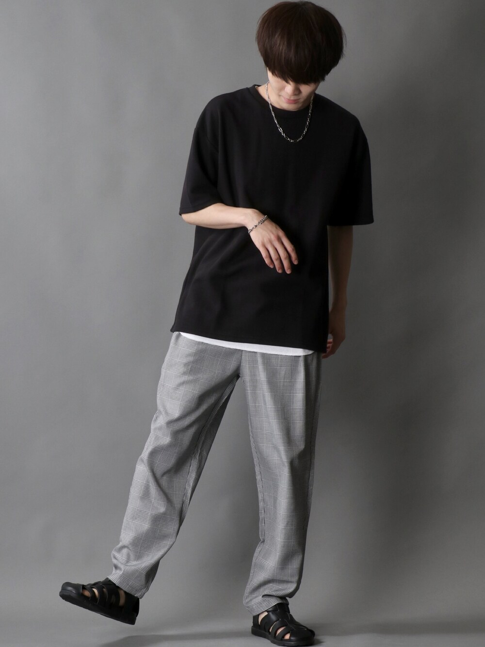 グレー系のチノパンツ、ブラック系のTシャツ/カットソー、シルバー系のネックレスを着用したメンズの夏コーディネートの1枚目の写真