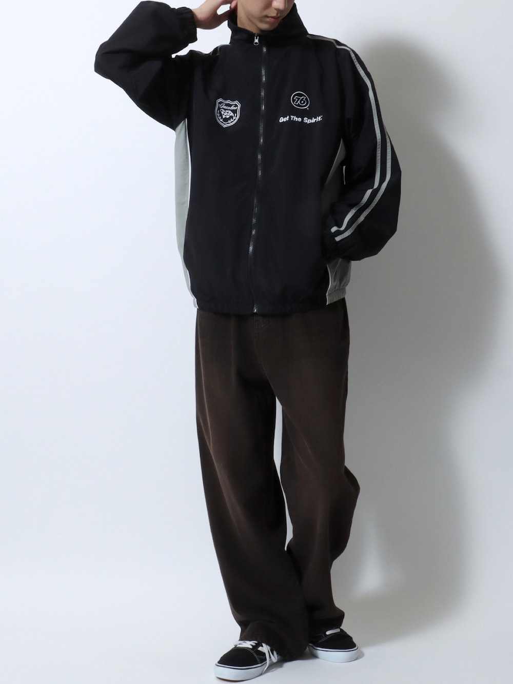 ブラック系のナイロンジャケット、ブラック系のデニムパンツ、ブラック系のスニーカーを着用したメンズの春コーディネートの1枚目の写真