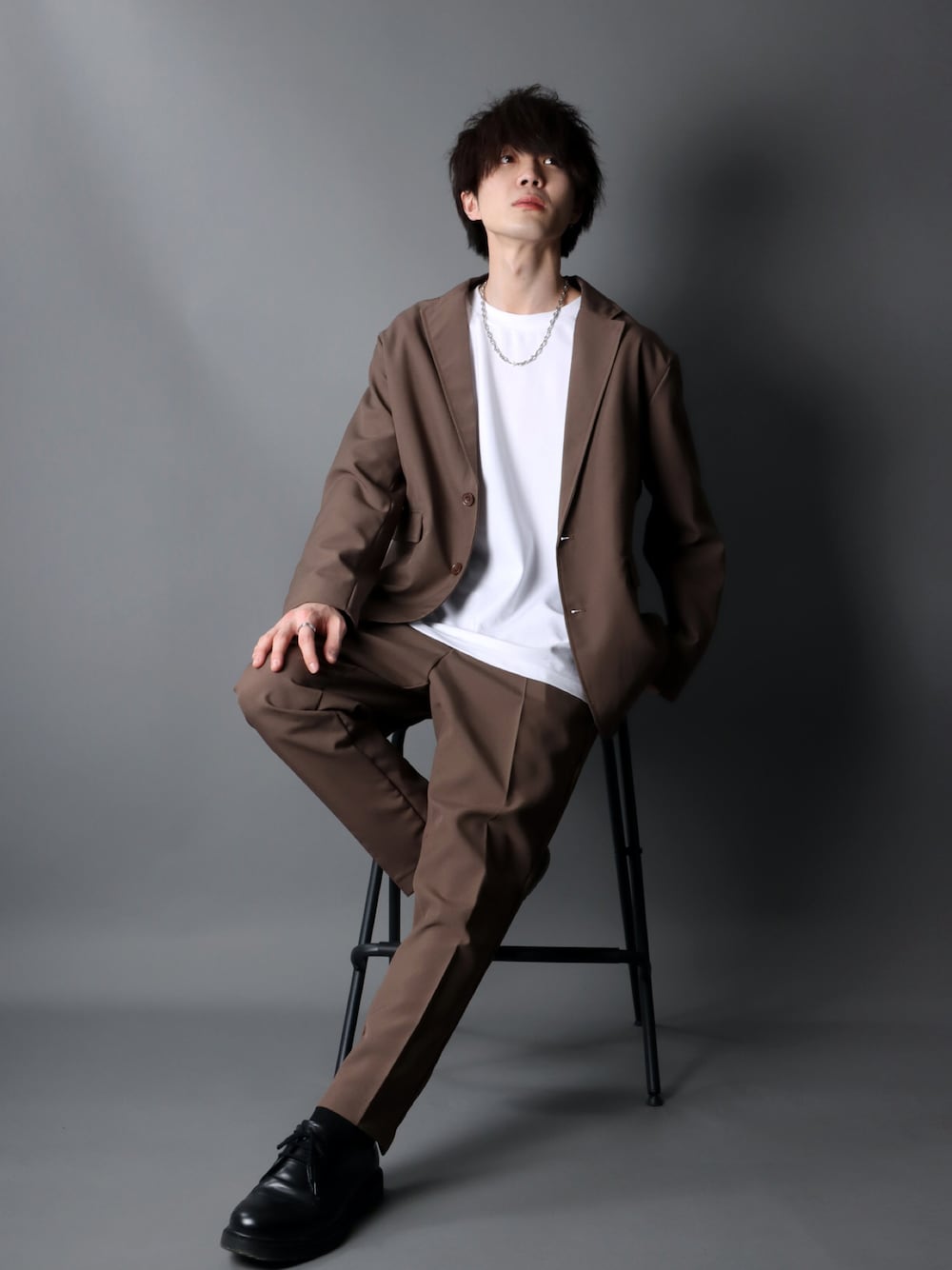 ブラウン系のセットアップ、ホワイト系のTシャツ/カットソー、ブラック系のブーツを着用したメンズの春コーディネートの1枚目の写真