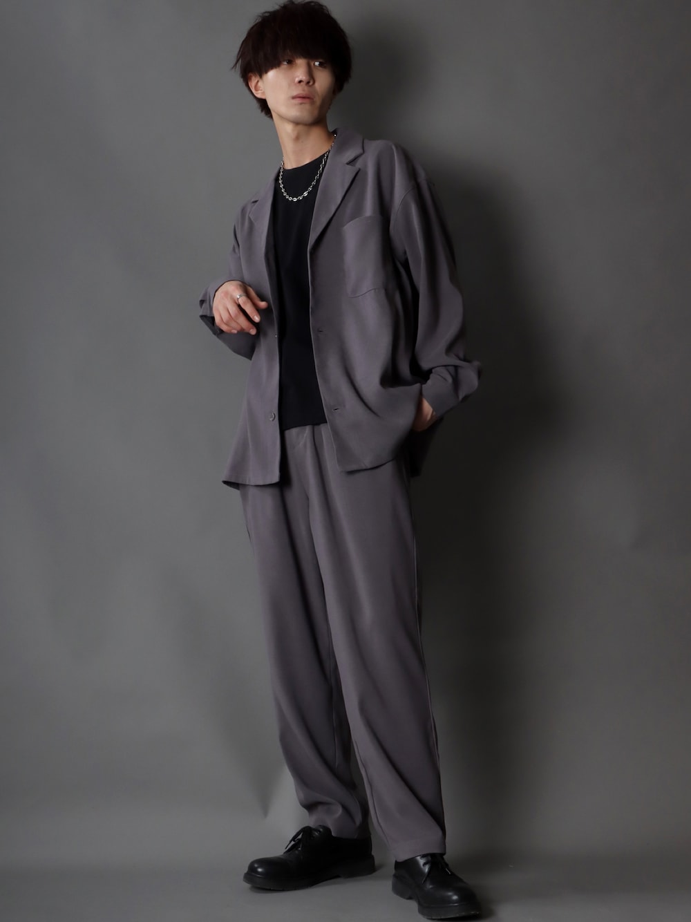 グレー系のセットアップ、ブラック系のTシャツ/カットソー、ブラック系のブーツを着用したメンズの秋コーディネートの1枚目の写真