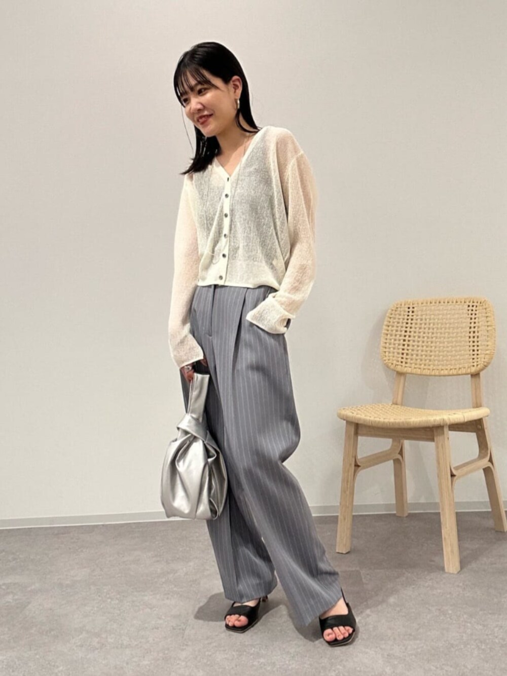 ブラック系のサンダル、シルバー系のビジネスバッグ、その他のスラックスを着用したレディースの夏コーディネートの1枚目の写真