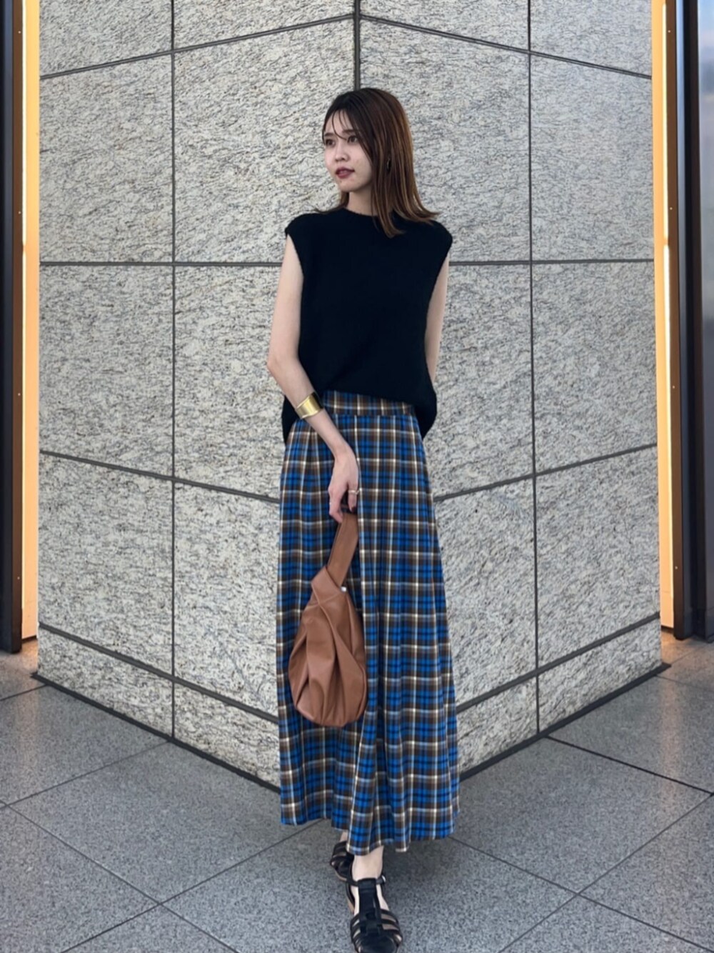 ブラック系のサンダル、ベージュ系のビジネスバッグ、ブラック系のニット/セーターを着用したレディースの夏コーディネートの1枚目の写真