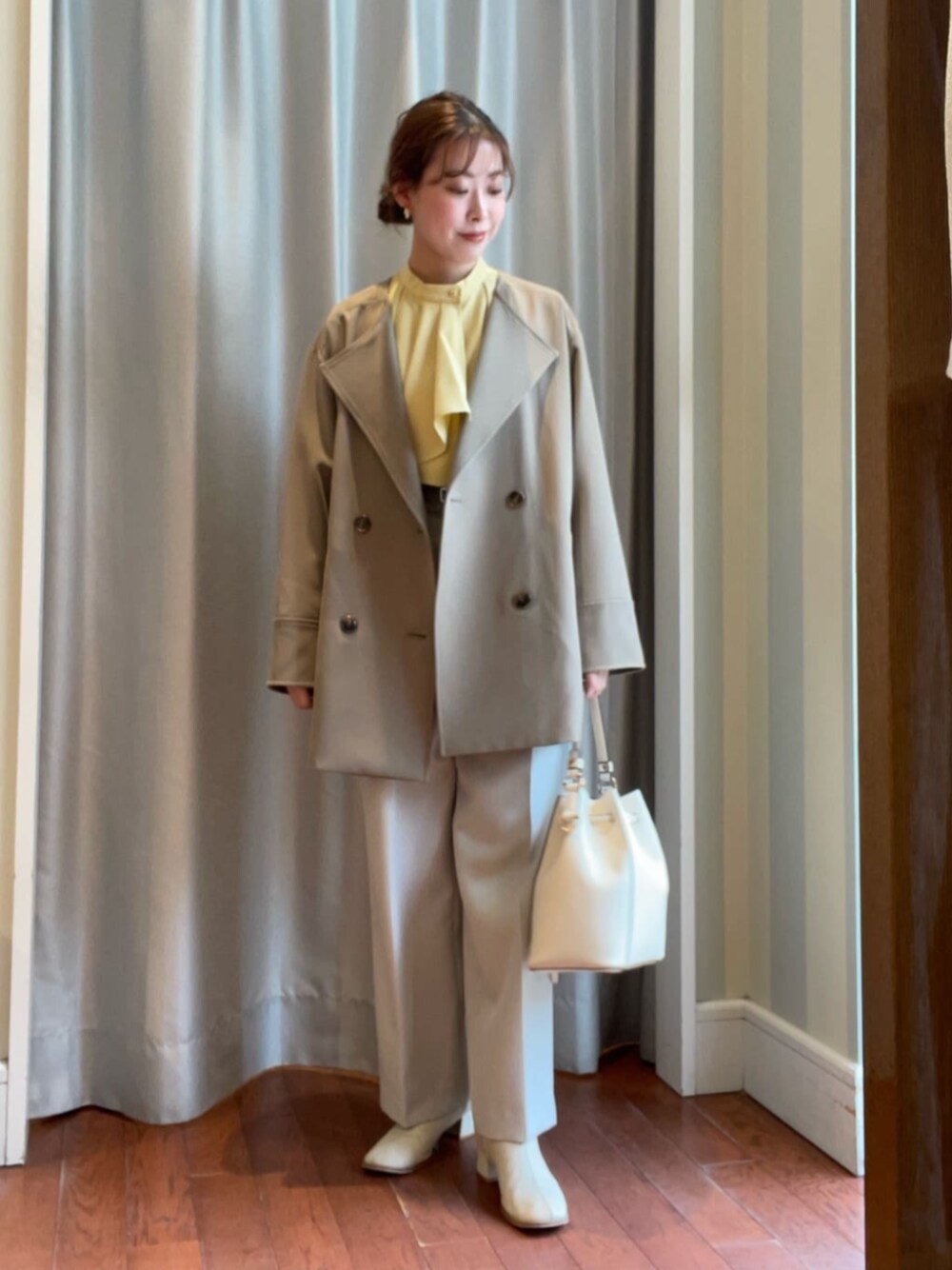 ホワイト系のショルダーバッグ、イエロー系のシャツ/ブラウス、ホワイト系のスラックスを着用したレディースの春コーディネートの1枚目の写真