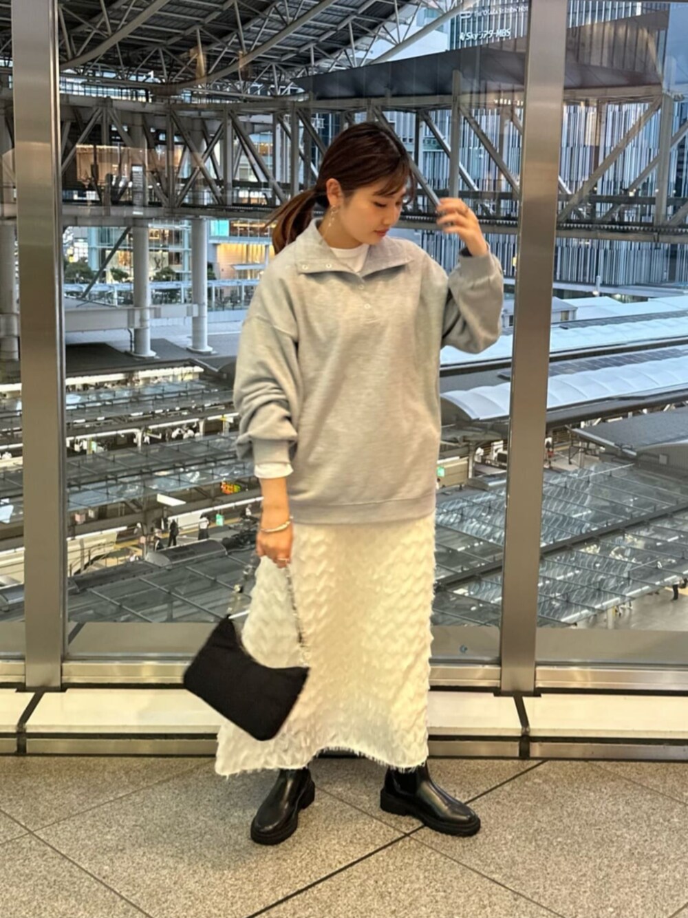 ブラック系のビジネスバッグ、ブラック系のブーツ、ホワイト系のTシャツ/カットソーを着用したレディースの秋コーディネートの1枚目の写真