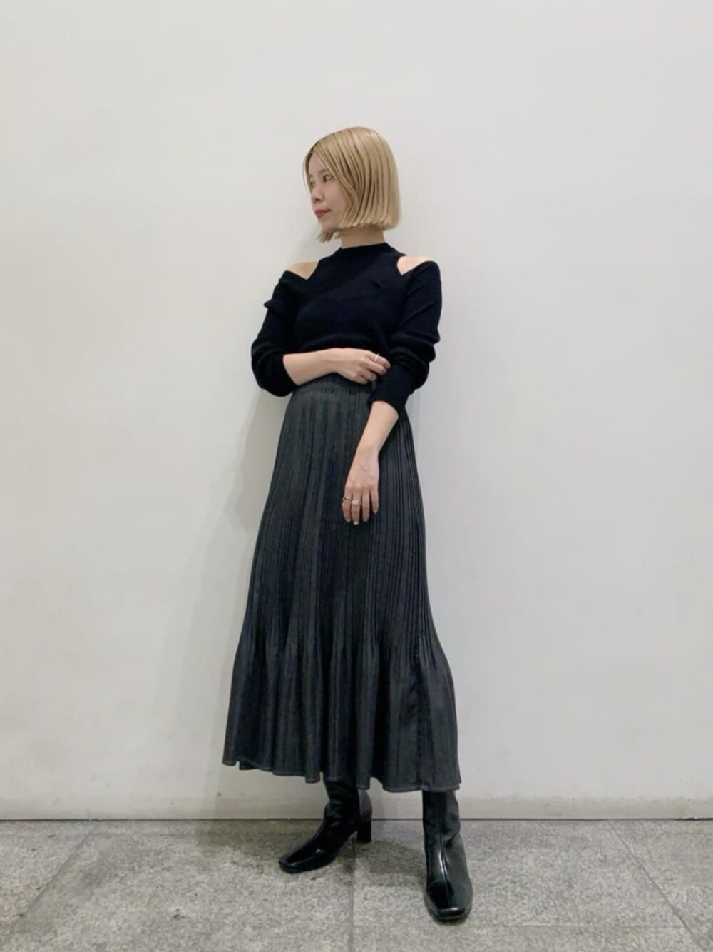 ブラック系のニット/セーター、ブラック系のブーツ、グレー系のスカートを着用したレディースの秋コーディネートの1枚目の写真