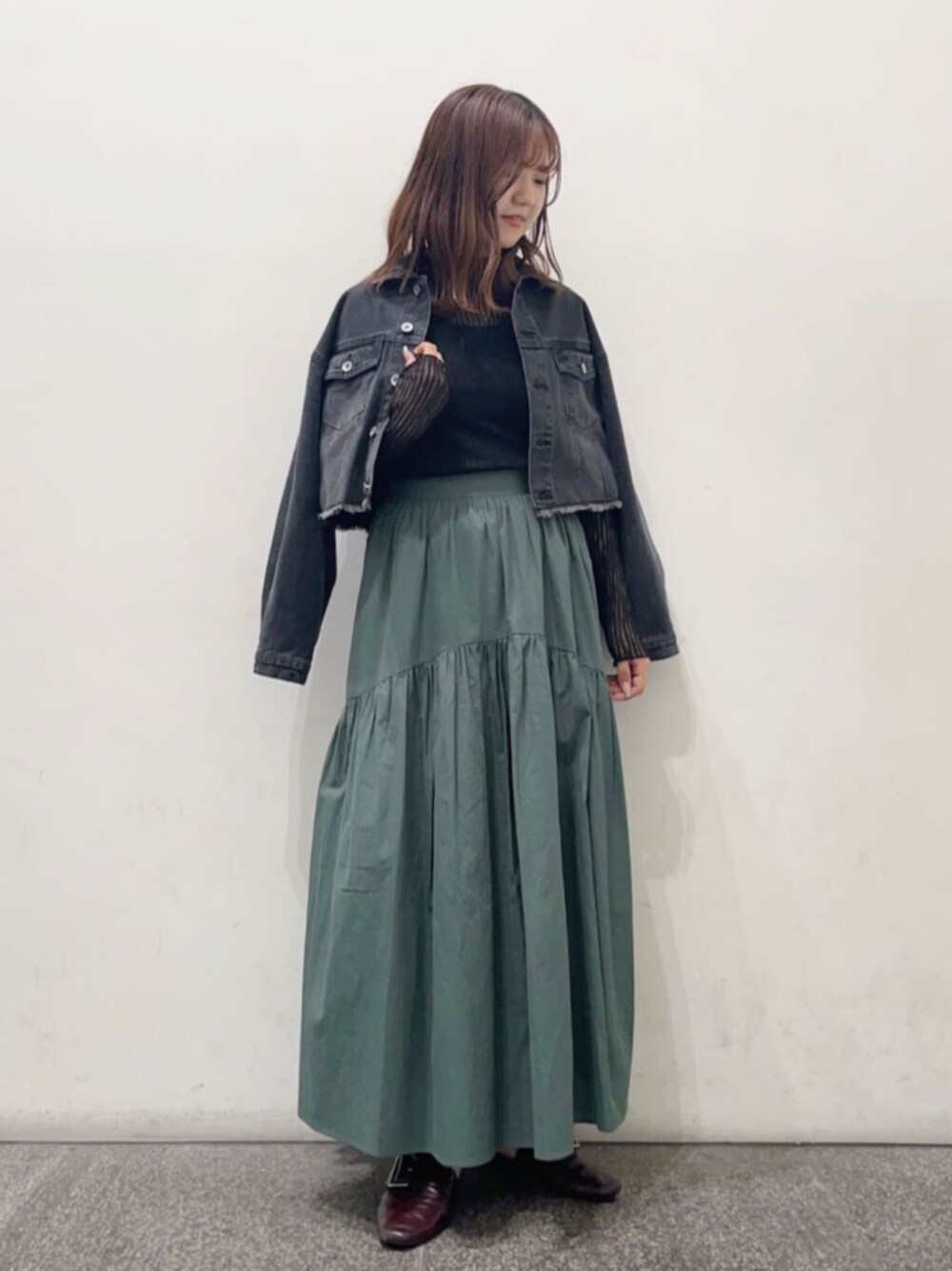 ブラック系のTシャツ/カットソー、グリーン系のスカート、ブラック系のデニムジャケットを着用したレディースの秋コーディネートの1枚目の写真