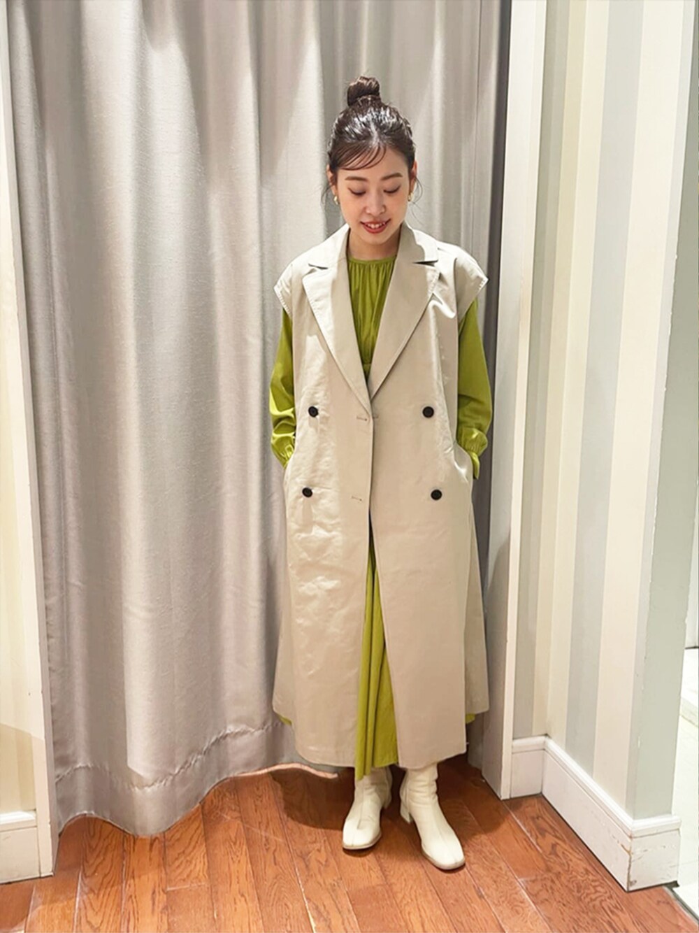 ベージュ系のトレンチコート、イエロー系のワンピースを着用したレディースの春コーディネートの1枚目の写真