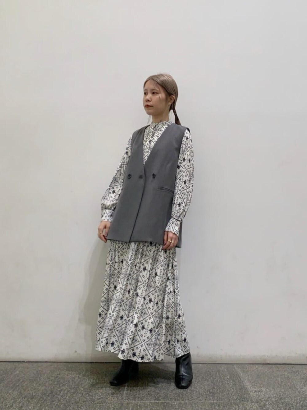 ブラック系のブーツ、ホワイト系のワンピース、グレー系のベストを着用したレディースの冬コーディネートの1枚目の写真