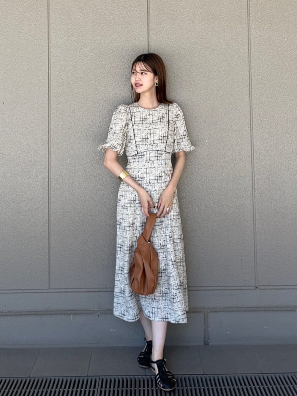 ブラック系のサンダル、ベージュ系のビジネスバッグ、ホワイト系のワンピースを着用したレディースの夏コーディネートの1枚目の写真