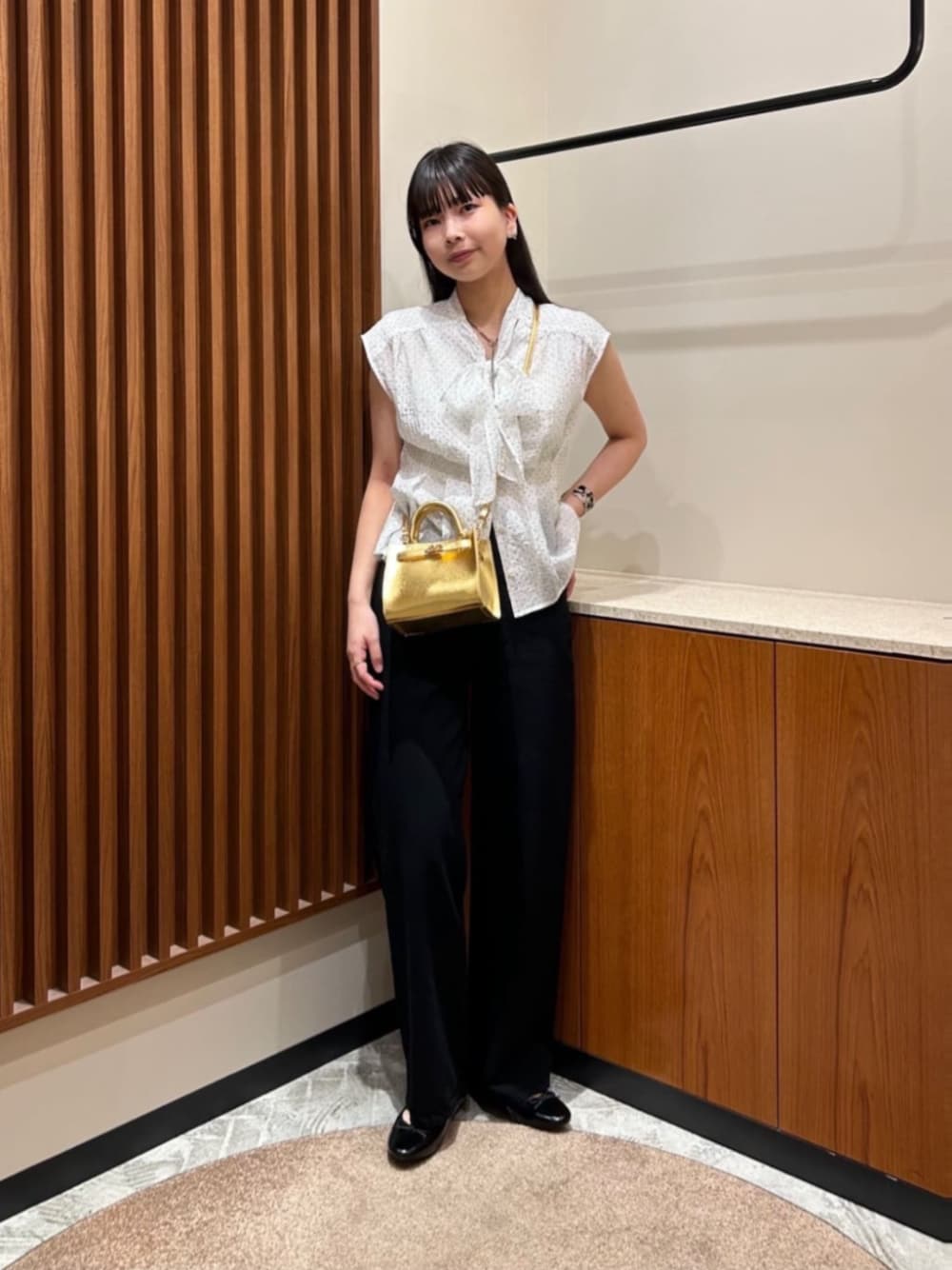 ブラック系のパンプス、ゴールド系のショルダーバッグ、ホワイト系のシャツ/ブラウスを着用したレディースの夏コーディネートの1枚目の写真
