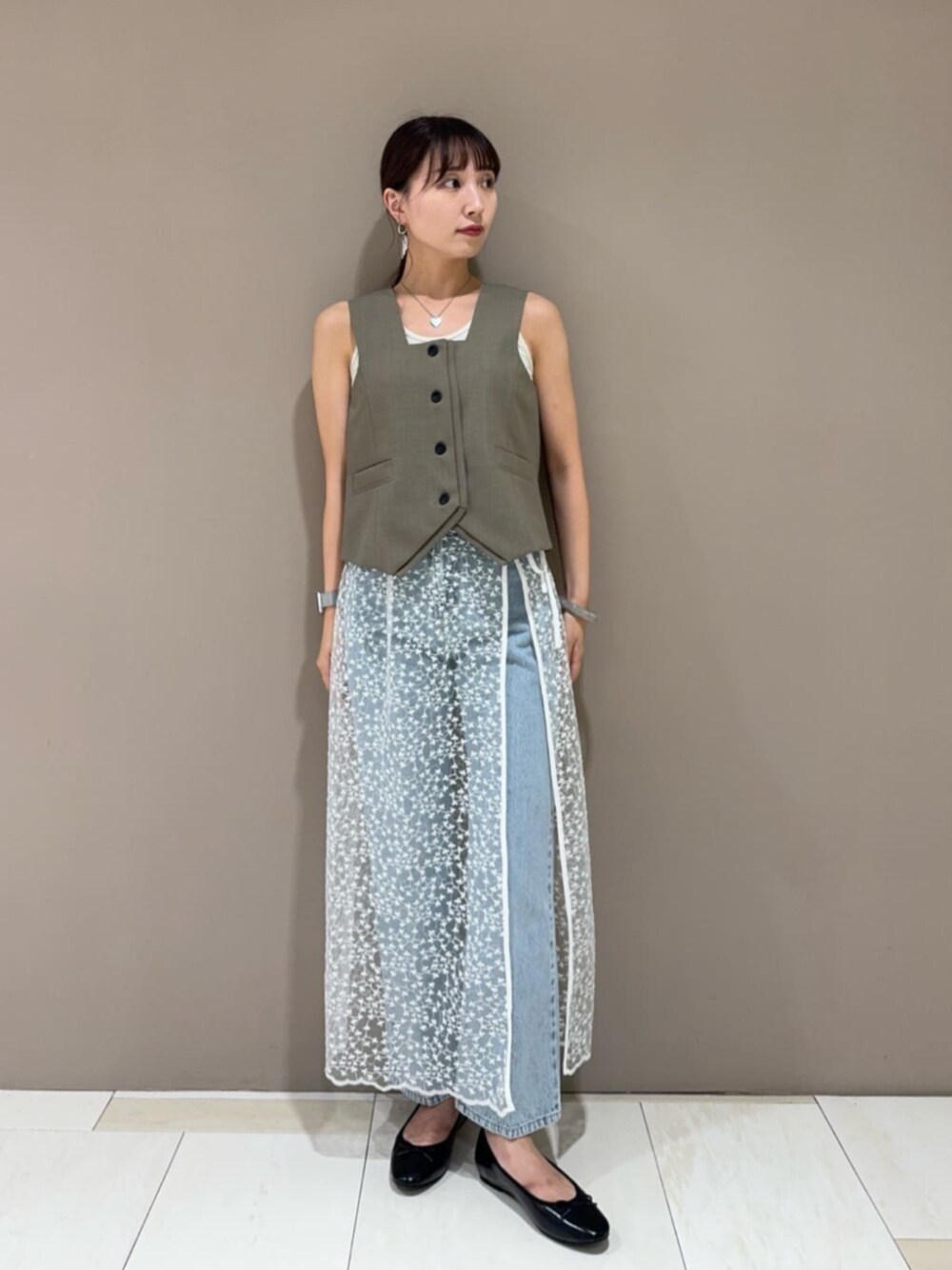 ブラック系のパンプス、ホワイト系のスカート、ブラウン系のベストを着用したレディースの夏コーディネートの1枚目の写真