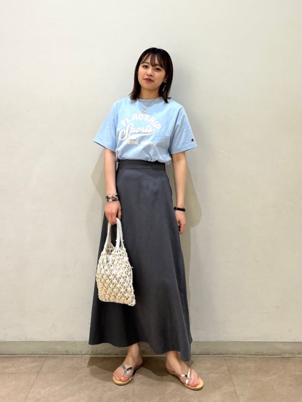 ホワイト系のショルダーバッグ、グレー系のスカート、シルバー系のサンダルを着用したレディースの春コーディネートの1枚目の写真