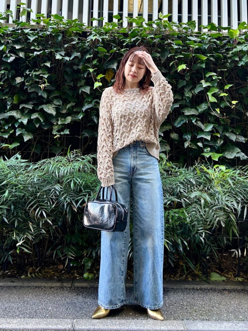 ゴールド系のパンプス、ブラック系のボストンバッグ、ブルー系のデニムパンツを着用したレディースの冬コーディネートの1枚目の写真