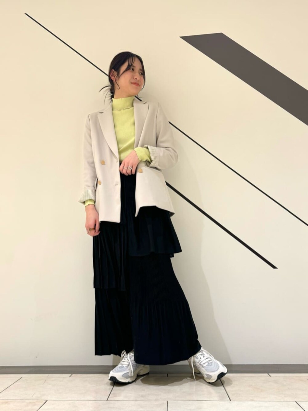 ブラック系のスカート、イエロー系のニット/セーター、ベージュ系のテーラードジャケットを着用したレディースの春コーディネートの1枚目の写真