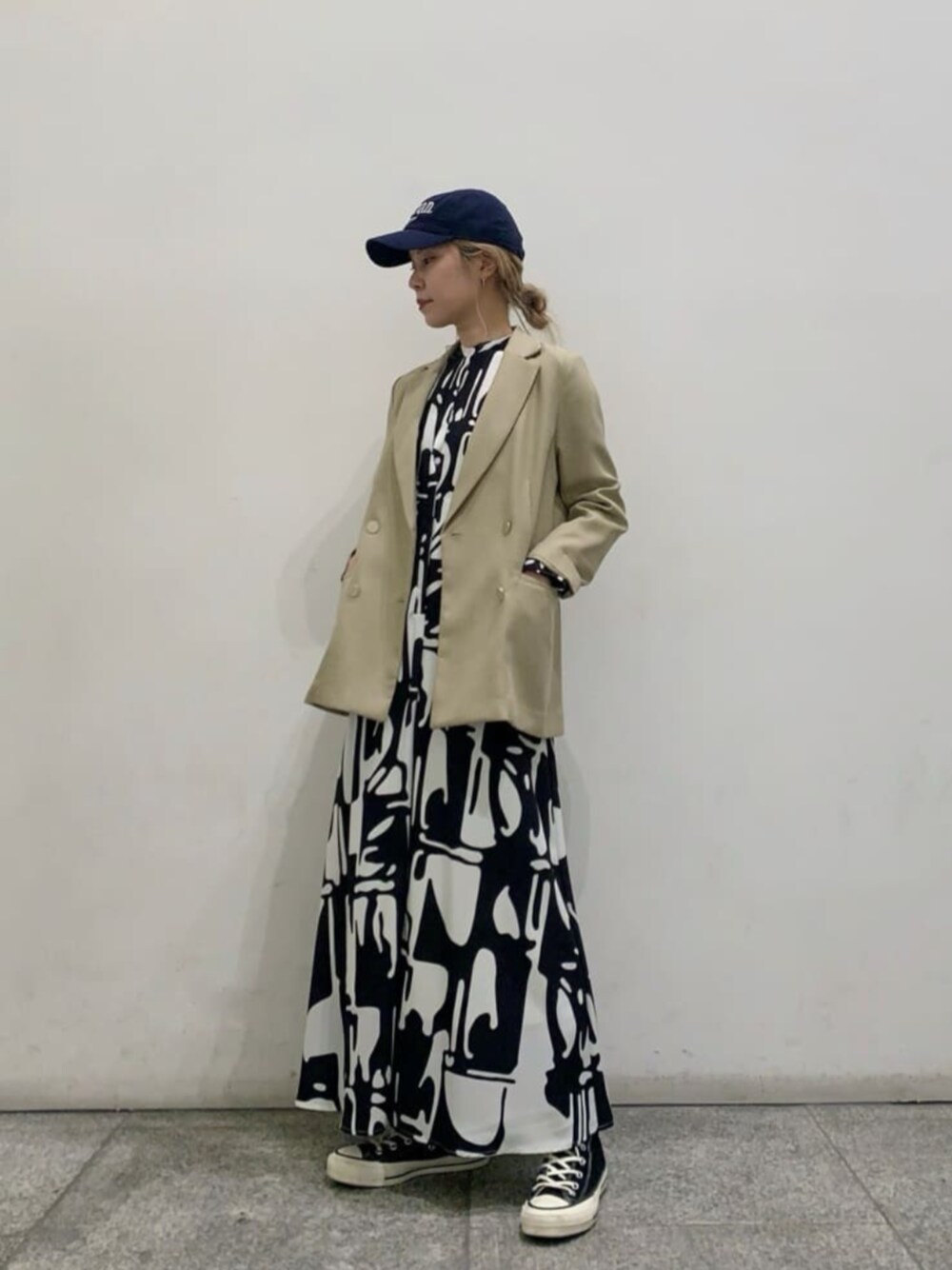 ベージュ系のテーラードジャケット、ブラック系のワンピースを着用したレディースの春コーディネートの1枚目の写真