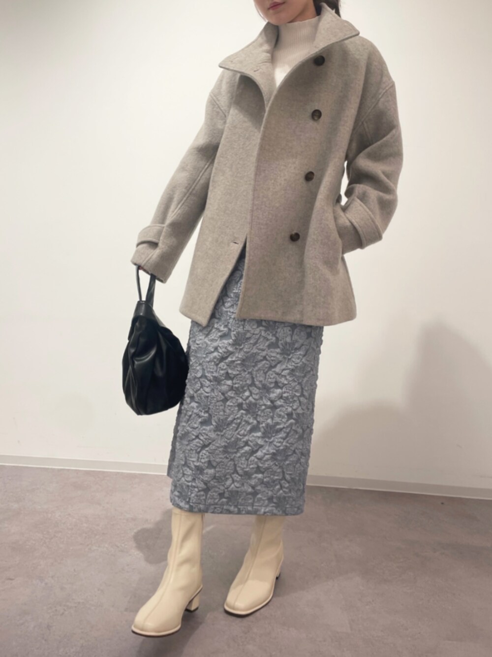 ブラック系のビジネスバッグ、ホワイト系のブーツ、ホワイト系のニット/セーターを着用したレディースの冬コーディネートの1枚目の写真