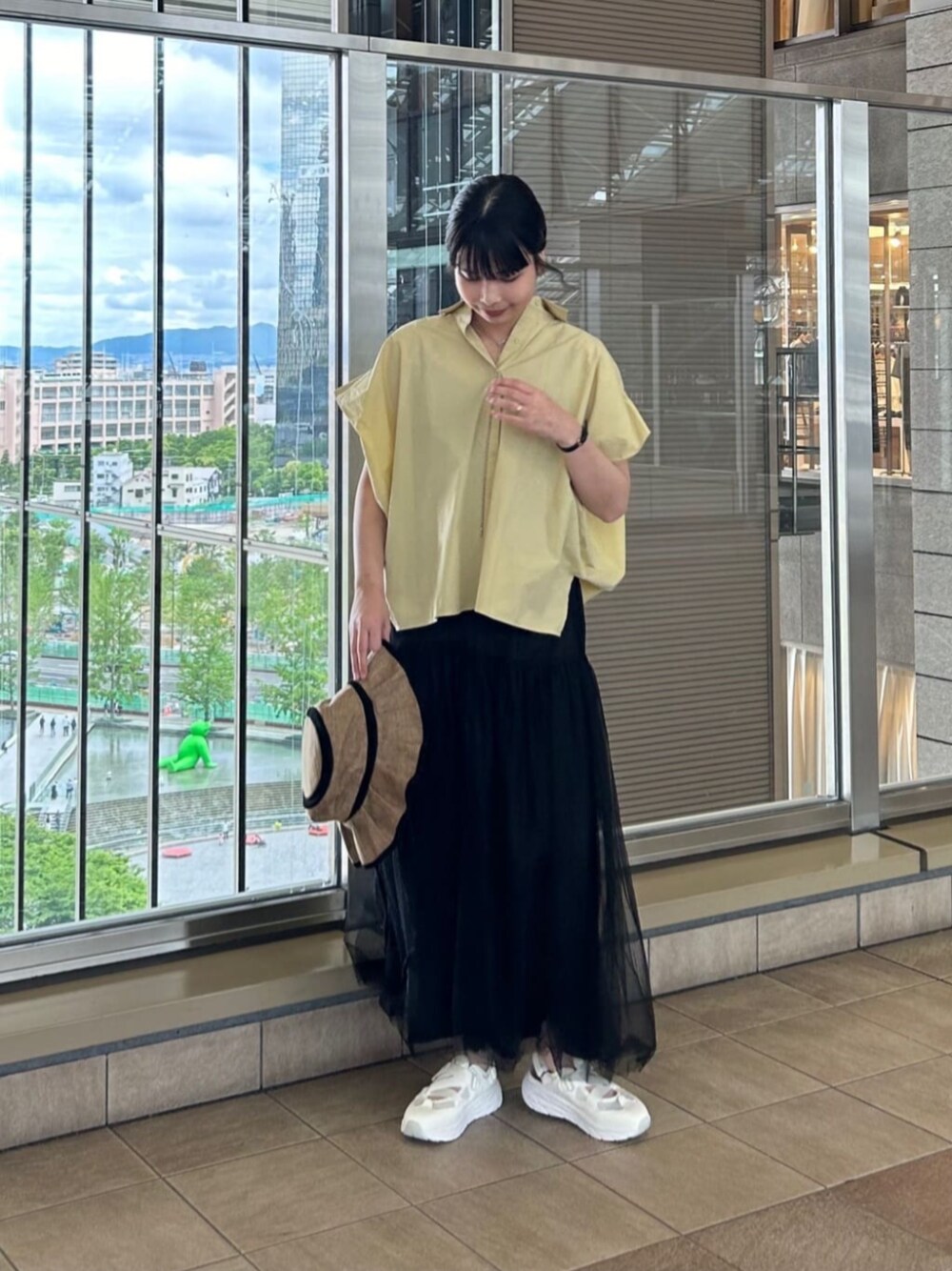 ホワイト系のスニーカー、イエロー系のシャツ/ブラウス、ブラック系のスカートを着用したレディースの春コーディネートの1枚目の写真